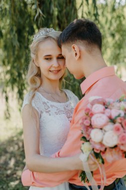 Gelin ve damat gün açık havada yürüyüş düğününde doğa bahar. Gelin Çift, mutlu yeni evli kadın ve yeşil park kucaklayan adam. Sevgi dolu evlilik çift açık. Gelin ve damat, düğün çekim