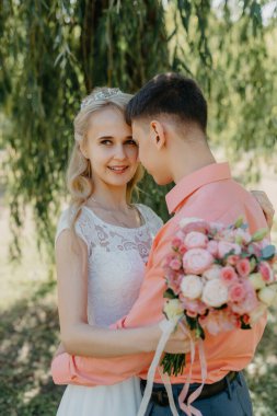 Gelin ve damat gün açık havada yürüyüş düğününde doğa bahar. Gelin Çift, mutlu yeni evli kadın ve yeşil park kucaklayan adam. Sevgi dolu evlilik çift açık. Gelin ve damat, düğün çekim