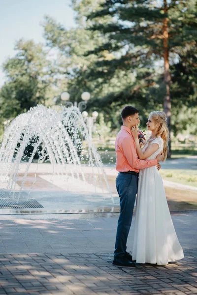 Szczęśliwa panna młoda i pan młody na ślubnym spacerze przy fontannie. Panna młoda i pan młody przeżywają romantyczny moment w dniu ślubu. — Zdjęcie stockowe