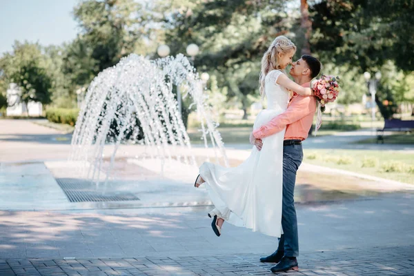 Happy bride and groom on wedding walk near fountain. Bride and groom having a romantic moment on their wedding day. — Stock Photo, Image