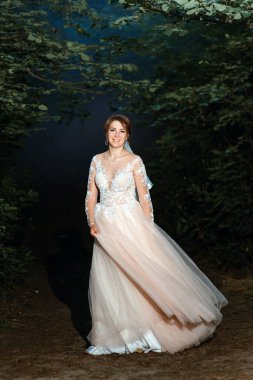 Doğada dönen muhteşem gelinlik içinde güzel, genç bir gelin. Mutluluk, eğlence. Günbatımında ormanda dans eden beyaz elbiseli güzel, şık, sarışın gelin. Güzel bir kadın.