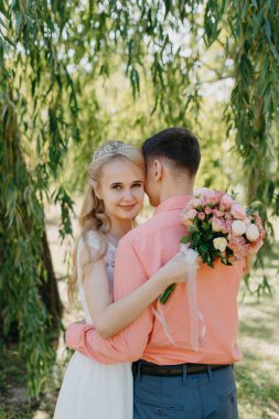 Gelin ve damat gün açık havada yürüyüş düğününde doğa bahar. Gelin Çift, mutlu yeni evli kadın ve yeşil park kucaklayan adam. Sevgi dolu evlilik çift açık. Gelin ve damat, düğün çekim