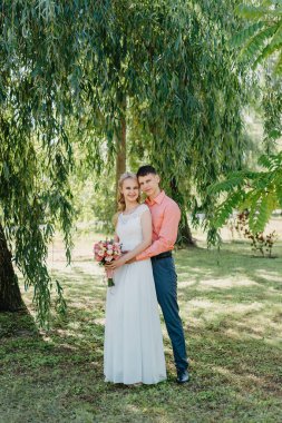 Gelin ve damat gün açık havada yürüyüş düğününde doğa bahar. Gelin Çift, mutlu yeni evli kadın ve yeşil park kucaklayan adam. Sevgi dolu evlilik çift açık. Gelin ve damat, düğün çekim