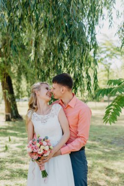 Gelin ve damat gün açık havada yürüyüş düğününde doğa bahar. Gelin Çift, mutlu yeni evli kadın ve yeşil park kucaklayan adam. Sevgi dolu evlilik çift açık. Gelin ve damat, düğün çekim