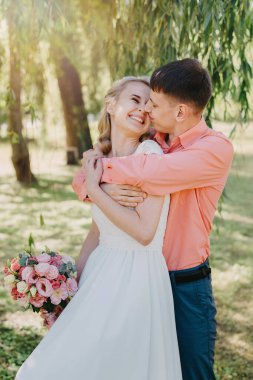 Gelin ve damat gün açık havada yürüyüş düğününde doğa bahar. Gelin Çift, mutlu yeni evli kadın ve yeşil park kucaklayan adam. Sevgi dolu evlilik çift açık. Gelin ve damat, düğün çekim