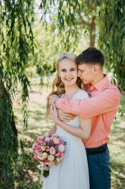 Gelin ve damat gün açık havada yürüyüş düğününde doğa bahar. Gelin Çift, mutlu yeni evli kadın ve yeşil park kucaklayan adam. Sevgi dolu evlilik çift açık. Gelin ve damat, düğün çekim