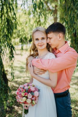 Gelin ve damat gün açık havada yürüyüş düğününde doğa bahar. Gelin Çift, mutlu yeni evli kadın ve yeşil park kucaklayan adam. Sevgi dolu evlilik çift açık. Gelin ve damat, düğün çekim