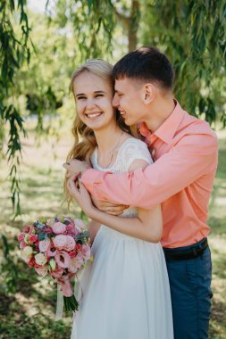 Gelin ve damat gün açık havada yürüyüş düğününde doğa bahar. Gelin Çift, mutlu yeni evli kadın ve yeşil park kucaklayan adam. Sevgi dolu evlilik çift açık. Gelin ve damat, düğün çekim