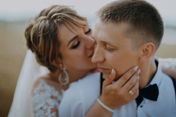 Hot woman showing tenderness man in garden. Portrait of sexy couple expressing feelings in park. Close up gorgeous bride and groom kissing on wedding ceremony outdoors. Bride and groom kisses tenderly — стоковое фото