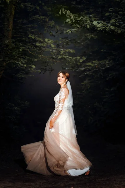 Красивая молодая невеста в великолепном свадебном платье, вращающемся в природе, счастье, веселье. красивая романтическая стильная блондинка невеста в белом платье танцует в лесу на закате. красивая женщина в — стоковое фото
