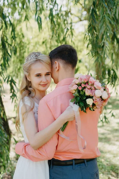 Novia y novio en el día de la boda caminando al aire libre en la naturaleza de primavera. Pareja nupcial, feliz mujer recién casada y hombre abrazándose en el parque verde. Amar pareja de boda al aire libre. Boda de novia y novio en —  Fotos de Stock