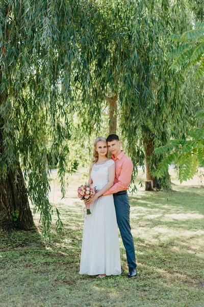 Bruid en bruidegom op de bruiloft dag buitenshuis lopen op lente natuur. Bruidspaar, Happy kersverse vrouw en man omarmen in groen park. Lief bruidspaar buiten. Bruiloft shot van de bruid en bruidegom in — Stockfoto