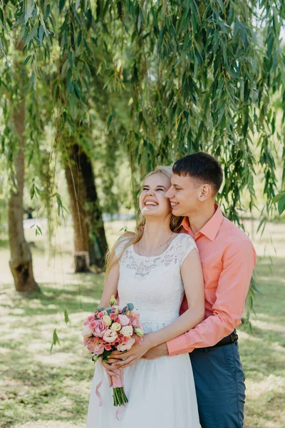 Gelin ve damat gün açık havada yürüyüş düğününde doğa bahar. Gelin Çift, mutlu yeni evli kadın ve yeşil park kucaklayan adam. Sevgi dolu evlilik çift açık. Gelin ve damat, düğün çekim