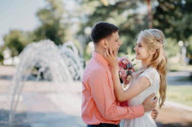 Gelin ve damat fıskiyenin yanında düğün yürüyüşünde. Gelin ve damat düğün günlerinde romantik anlar yaşıyorlar..