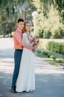 Gelin ve damat gün açık havada yürüyüş düğününde doğa bahar. Gelin Çift, mutlu yeni evli kadın ve yeşil park kucaklayan adam. Sevgi dolu evlilik çift açık. Gelin ve damat, düğün çekim