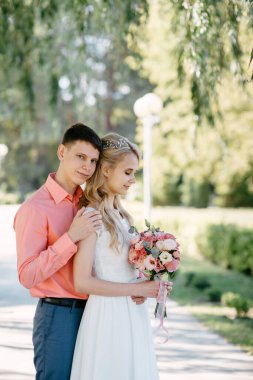 Gelin ve damat gün açık havada yürüyüş düğününde doğa bahar. Gelin Çift, mutlu yeni evli kadın ve yeşil park kucaklayan adam. Sevgi dolu evlilik çift açık. Gelin ve damat, düğün çekim