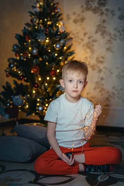 Adorable little baby boy sitting in front of a christmas tree. Christmas Child Open Present Gift, Happy Baby Boy looking to Magic Light in Box, Kid sitting front of Xmas Tree — Stock Photo, Image