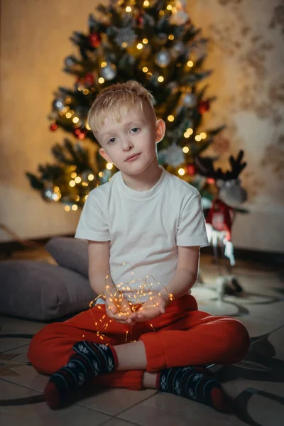 Adorable little baby boy sitting in front of a christmas tree. Christmas Child Open Present Gift, Happy Baby Boy looking to Magic Light in Box, Kid sitting front of Xmas Tree — Stock Photo, Image