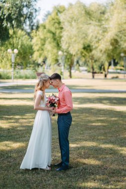 Gelin ve damat gün açık havada yürüyüş düğününde doğa bahar. Gelin Çift, mutlu yeni evli kadın ve yeşil park kucaklayan adam. Sevgi dolu evlilik çift açık. Gelin ve damat, düğün çekim