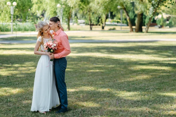 Novia y novio en el día de la boda caminando al aire libre en la naturaleza de primavera. Pareja nupcial, feliz mujer recién casada y hombre abrazándose en el parque verde. Amar pareja de boda al aire libre. Boda de novia y novio en —  Fotos de Stock