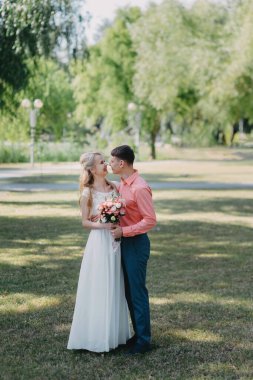 Gelin ve damat gün açık havada yürüyüş düğününde doğa bahar. Gelin Çift, mutlu yeni evli kadın ve yeşil park kucaklayan adam. Sevgi dolu evlilik çift açık. Gelin ve damat, düğün çekim