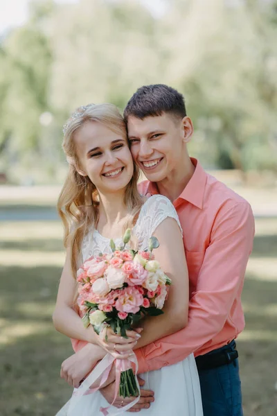 Menyasszony és a vőlegény az esküvő nap séta kint a tavaszi természet. Nászutas pár, boldog Newlywed nő és férfi átfogó zöld parkban. Szerető szabadtéri esküvő házaspár. A menyasszony és a vőlegény az esküvő shot — Stock Fotó