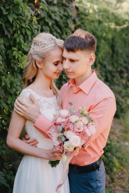 Gelin ve damat gün açık havada yürüyüş düğününde doğa bahar. Gelin Çift, mutlu yeni evli kadın ve yeşil park kucaklayan adam. Sevgi dolu evlilik çift açık. Gelin ve damat, düğün çekim