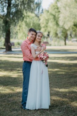 Gelin ve damat gün açık havada yürüyüş düğününde doğa bahar. Gelin Çift, mutlu yeni evli kadın ve yeşil park kucaklayan adam. Sevgi dolu evlilik çift açık. Gelin ve damat, düğün çekim