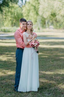 Gelin ve damat gün açık havada yürüyüş düğününde doğa bahar. Gelin Çift, mutlu yeni evli kadın ve yeşil park kucaklayan adam. Sevgi dolu evlilik çift açık. Gelin ve damat, düğün çekim