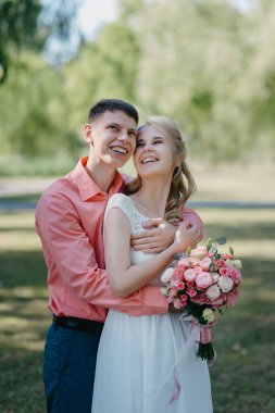 Gelin ve damat gün açık havada yürüyüş düğününde doğa bahar. Gelin Çift, mutlu yeni evli kadın ve yeşil park kucaklayan adam. Sevgi dolu evlilik çift açık. Gelin ve damat, düğün çekim