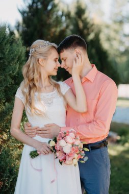 Gelin ve damat gün açık havada yürüyüş düğününde doğa bahar. Gelin Çift, mutlu yeni evli kadın ve yeşil park kucaklayan adam. Sevgi dolu evlilik çift açık. Gelin ve damat, düğün çekim