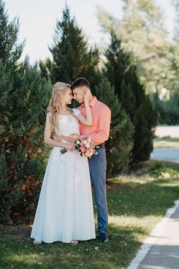 Gelin ve damat gün açık havada yürüyüş düğününde doğa bahar. Gelin Çift, mutlu yeni evli kadın ve yeşil park kucaklayan adam. Sevgi dolu evlilik çift açık. Gelin ve damat, düğün çekim