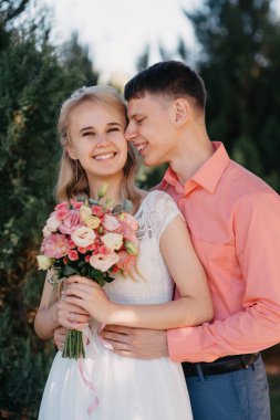 Gelin ve damat gün açık havada yürüyüş düğününde doğa bahar. Gelin Çift, mutlu yeni evli kadın ve yeşil park kucaklayan adam. Sevgi dolu evlilik çift açık. Gelin ve damat, düğün çekim