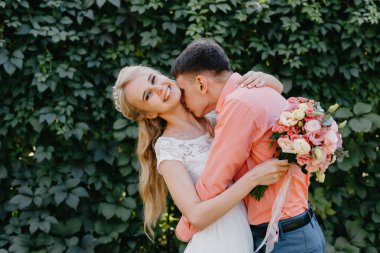 Gelin ve damat gün açık havada yürüyüş düğününde doğa bahar. Gelin Çift, mutlu yeni evli kadın ve yeşil park kucaklayan adam. Sevgi dolu evlilik çift açık. Gelin ve damat, düğün çekim