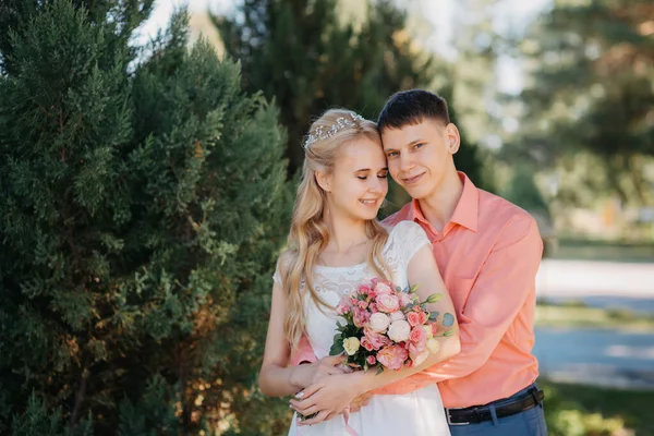 Novia y novio en el día de la boda caminando al aire libre en la naturaleza de primavera. Pareja nupcial, feliz mujer recién casada y hombre abrazándose en el parque verde. Amar pareja de boda al aire libre. Boda de novia y novio en — Foto de Stock