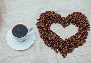 Bir fincan Coffe. Kahve çekirdekleri kalp şeklinde. kahve çekirdekleri beyaz arka plan üzerinde izole. kavrulmuş kahve çekirdekleri, bir arka plan olarak kullanılabilir.