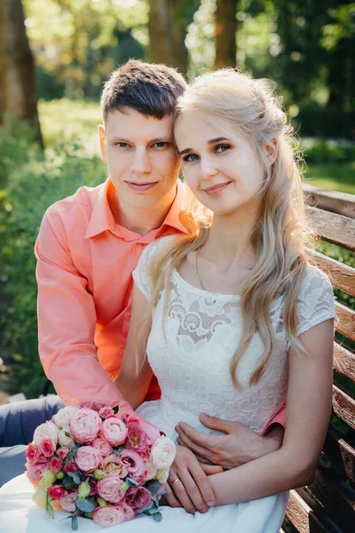 Novia y novio en el día de la boda caminando al aire libre en la naturaleza de primavera. Pareja nupcial, feliz mujer recién casada y hombre abrazándose en el parque verde. Amar pareja de boda al aire libre. Boda de novia y novio en — Foto de Stock