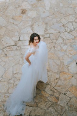 Eski şatoda yürüyen gelinlik lüks elbiseler içinde şık bir gelin. Şatoda yürüyen günbatımında lüks gelinlik içinde şık bir gelin. Güzel, zarif.