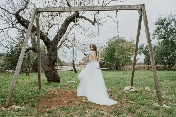 Feliz pareja sonriente elegante caminando en Toscana, Italia en el día de su boda. Recién casados con el columpio en el parque. Los novios caminan por la calle con las manos. Una pareja joven y elegante camina — Foto de Stock