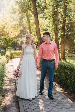 Gelin ve damat gün açık havada yürüyüş düğününde doğa bahar. Gelin Çift, mutlu yeni evli kadın ve yeşil park kucaklayan adam. Sevgi dolu evlilik çift açık. Gelin ve damat, düğün çekim