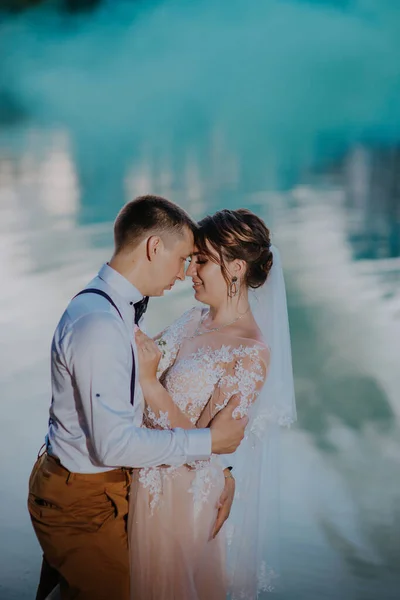 Bride and groom with the blue and yellow colored smoke bombs in the summer park. The bride and groom with the colored smoke at the background of summer forest. Wedding couple runs color smoke in the — Fotografia de Stock
