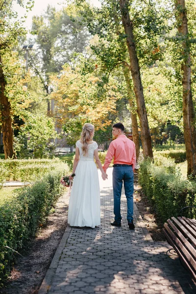 Novia y novio en el día de la boda caminando al aire libre en la naturaleza de primavera. Pareja nupcial, feliz mujer recién casada y hombre abrazándose en el parque verde. Amar pareja de boda al aire libre. Boda de novia y novio en —  Fotos de Stock