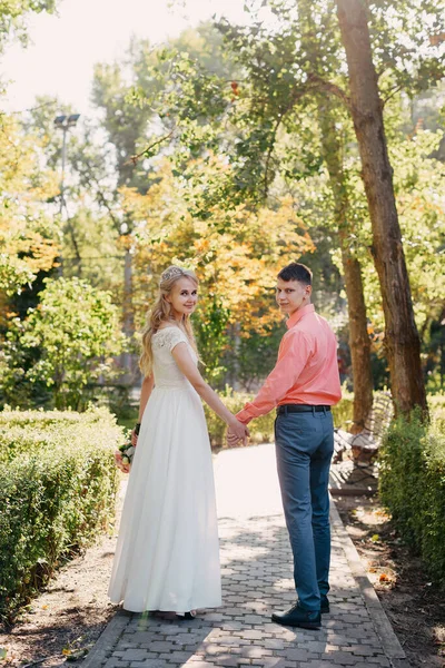 Noiva e noivo no dia do casamento andando ao ar livre na natureza de primavera. Casal nupcial, mulher recém-casada feliz e homem abraçando no parque verde. Casal de amor ao ar livre. Tiro de casamento de noiva e noivo em — Fotografia de Stock