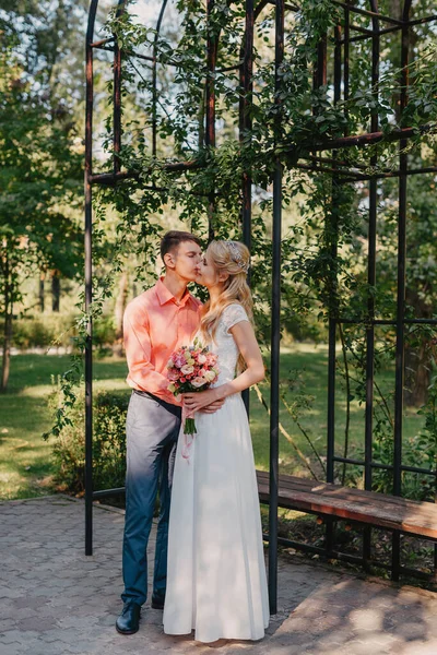 Novia y novio en el día de la boda caminando al aire libre en la naturaleza de primavera. Pareja nupcial, feliz mujer recién casada y hombre abrazándose en el parque verde. Amar pareja de boda al aire libre. Boda de novia y novio en —  Fotos de Stock