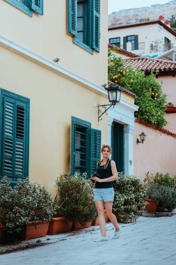 Güzel bir kız elinde bir kamerayla eski bir Avrupa kasabasının caddesinde yürüyor. Sokakta yürüyen bir turist kızın portresi..