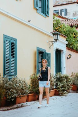 Güzel bir kız elinde bir kamerayla eski bir Avrupa kasabasının caddesinde yürüyor. Sokakta yürüyen bir turist kızın portresi..