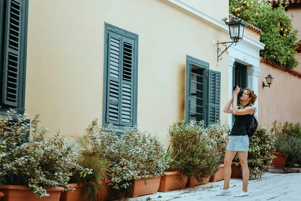 Güzel bir kız elinde bir kamerayla eski bir Avrupa kasabasının caddesinde yürüyor. Sokakta yürüyen bir turist kızın portresi..