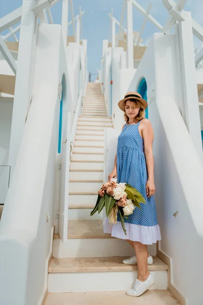 Mooi meisje wandelen met boeket bloemen langs de straat van Santorini eiland, een oude Europese stad, Griekenland. Portret van een toeristisch meisje op straat. Liefdesverhaal zomer — Stockfoto