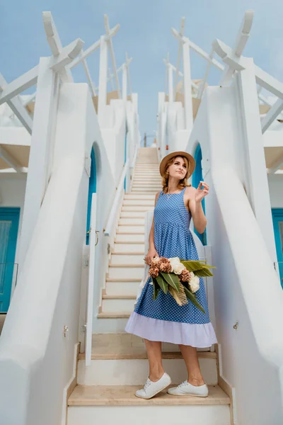 Mooi meisje wandelen met boeket bloemen langs de straat van Santorini eiland, een oude Europese stad, Griekenland. Portret van een toeristisch meisje op straat. Liefdesverhaal zomer — Stockfoto