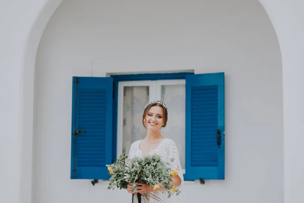 サントリーニ島、ギリシャ、人気の結婚式の目的地に青い窓の白い建築の背景に美しい花嫁 — ストック写真